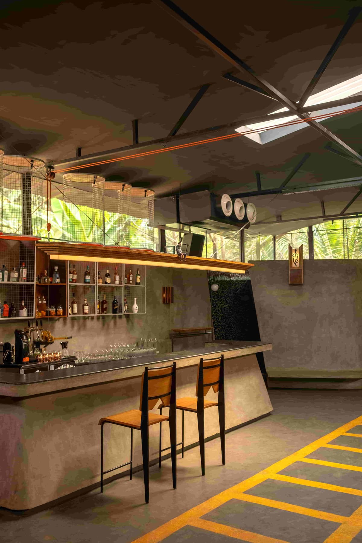 The bar counter in poured concrete with stepped plywood lamps